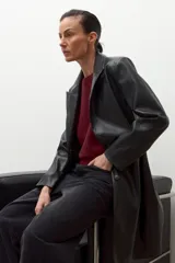 Blazer largo de eco cuero color negro, con solapas clásicas, cierre frontal con botones y diseño de corte recto.