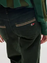 Pantalón de tiro medio confeccionado en pana color rojo, con corte holgado y detalle de línea lateral en contraste.