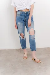 Jean azul de tiro medio y calce relaxed, con roturas amplias y desflecadas.