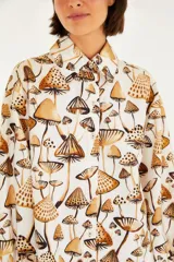 Camisa de manga larga con estampado de hongos en tonos marrones. Tiene cuello clásico, corte recto y abotonadura frontal.