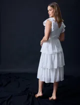 Vestido blanco de gasa con capas, marca Julia Jordan. Escote en V, manga corta con volados, corte en cintura y abertura central en espalda con cierre invisible.