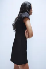 Vestido corto negro de cuello redondo con lazada, escote cuadrado y manga corta, con cierre en la espalda con cremallera oculta.