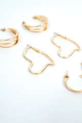 Set de tres pares de aros plateados de diseño variado: un par de argollas dobles, un par de aros con forma de corazón y un par de argollas pequeñas con textura rayada.
