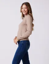 Buzo de tejido de punto color beige, con cuello alto y mangas largas. Presenta un diseño de calce ajustado con puños y ruedo acanalados.