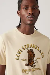 Remera color crema de corte clásico, con cuello redondo y manga corta. Estampado frontal con el logo de Levi's y un águila.