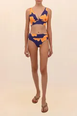 Top de bikini estilo Marilyn con estampado floral en tonos naranja y azul. Tiene tirantes anchos, coletas para amarre seguro y faja ancha para un soporte confiable.