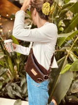 Riñonera de gamuza color chocolate con cierre azul marino y correa ajustable.