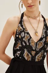 Vestido corto negro con volados en la falda y escote halter. El corpiño es de lentejuelas con diseño animal print en tonos negro, dorado y plateado.