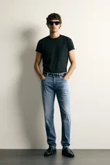 Jeans slim fit de color negro para hombre, con tiro medio, diseño de cinco bolsillos y cierre frontal con cremallera y botón.