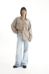 Camisa negra de pana, corte oversize, con cuello camisero, cierre frontal con botones, dos bolsillos con solapa en el pecho y mangas largas con puños abotonados.