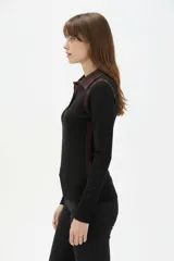 Remera de manga larga al cuerpo confeccionada en lyocell, con diseño color block que combina negro y marrón, cuello tipo camisa y botones frontales.