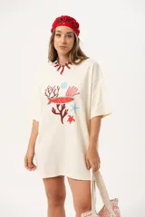 Remerón de corte oversize y largo extendido, color crudo, con estampa frontal de motivos marinos que incluye peces, corales, estrellas de mar y tortugas en tonos rojos y celestes.