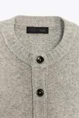 Chaqueta de punto de cuello redondo y manga larga, con cierre frontal de botones y acabados en rib.