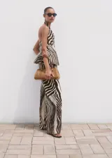 Pantalón wide leg de tiro medio con estampado de cebra, confeccionado en mezcla de lino y algodón. Cuenta con bolsillos laterales, trabillas para cinturón y cierre frontal oculto con botón, gancho y cremallera.