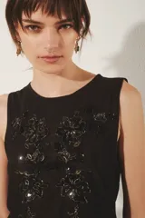 Top sin mangas de mesh con escote redondo y bordados florales hechos a mano a tono. Presenta un diseño sin forrería.