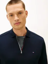 Chomba de manga larga Tommy Hilfiger de color azul marino, confeccionada en algodón con acabado Liquid Touch. Presenta cuello clásico, cierre frontal con cremallera corta y detalles tricolores en el interior de la abertura. Cuenta con puños acanalados y el logo bordado de la marca en el pecho.