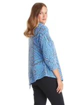Buzo de tejido soft labrado con diseño floral, cuello volcado con detalle de botones en la solapa, mangas tres cuartos con hombros caídos y ruedo asimétrico en punta.