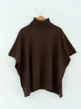 Poncho de tejido de punto color marrón chocolate, con cuello alto tipo polera y mangas cortas amplias. Presenta un diseño holgado con terminaciones acanaladas en el ruedo.
