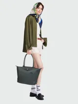 Bolso tote Longchamp modelo Le Pliage Green L, color marrón chocolate, confeccionado en lona de nylon reciclado con detalles en cuero ruso color marrón oscuro. Cuenta con cierre de cremallera y botón a presión, asas cortas para llevar al hombro y es plegable para facilitar su almacenamiento.