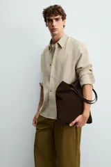 Bolso tipo shopper de diseño minimalista, confeccionado en piel con acabado de serraje. Cuenta con dos asas largas de mano y un compartimento principal espacioso con un bolsillo interior con cierre.