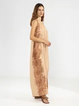 Vestido halter largo color beige con estampado exclusivo de Polonio de girasoles en tono marrón. Confeccionado en tejido liviano, fluye con naturalidad sobre el cuerpo, dejando los hombros al descubierto y con un largo hasta el tobillo.