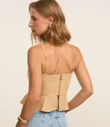 Blusa estilo corset color beige claro, con escote corazón y breteles finos. Presenta un corte ajustado en el torso y un volado peplum en el bajo.