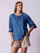 Blusa celeste de tencel con cuello redondo, escote en V y lazo de ajuste. Tiene cuello y escote calado y mangas 3/4 amplias con puño elastizado.