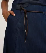 Falda midi de denim en corte evasé, con abertura frontal y cinturón fino de cuero sintético incluido. Confeccionada en algodón, presenta un diseño versátil y moderno.