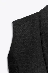 Top sin mangas confeccionado en tejido piqué, con escote cruzado tipo solapa y detalle de pliegues. Presenta una banda ancha ajustada en la cintura y un diseño de hombros caídos.