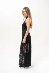 Vestido largo negro de encaje con cuello halter y espalda descubierta, con forro corto y falda translúcida.