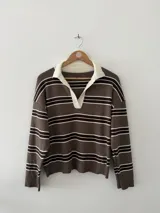 Sweater de tejido bremer a rayas horizontales en tonos marrón, blanco y negro, con cuello polo en color crema y mangas largas.