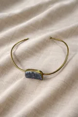 Gargantilla rígida dorada con dije de amatista rectangular en bruto.