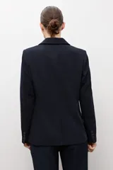 Blazer clásico color negro de corte entallado, con solapa de muesca, cierre de un botón frontal y bolsillos de ojal en los laterales.