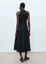 Vestido midi sin mangas, de corte evasé y cuello en pico. Presenta cierre frontal con botones, bolsillos laterales y cinturón ajustable a tono. Confeccionado en mezcla de lyocell y lino, incluye forro interior.