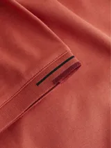 Chomba de piqué color ladrillo, con cuello polo de dos botones y logo bordado en el pecho. Presenta ribetes en cuello y mangas.