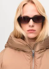 Chaqueta puffer corta color tostado con capucha, bolsillos laterales con ribete, cierre frontal con cremallera y diseño oversize acolchado.