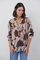 Camisa de manga larga con estampado floral en tonos marrones sobre fondo beige. Presenta cuello mao con escote en V y cierre frontal con botones.