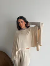 Conjunto de dos piezas de lanilla en color gris melange, compuesto por una blusa de corte amplio con mangas murciélago y escote bote, y un pantalón recto con bolsillos laterales.