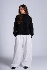 Sweater tejido de punto color blanco, con cuello alto tipo media polera, mangas largas y dobladillo asimétrico con aberturas laterales.
