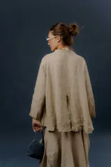 Chaqueta de lino color beige, de calce relajado, con escote en V, cierre frontal con botones y bolsillos frontales aplicados.