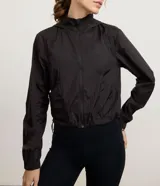 Campera cortavientos deportiva modelo cropped, color blanco traslúcido, con cierre frontal de cremallera, capucha estructurada, puños elásticos y bajo ajustable con cordón.
