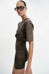 Vestido corto de manga corta y cuello redondo, confeccionado con mezcla de algodón. Presenta un diseño ajustado con drapeado lateral en la falda.