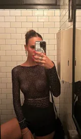 Body de red negro con mangas largas, cuello redondo y apliques de strass brillantes en toda la prenda. Presenta un diseño ajustado al cuerpo con una textura calada.