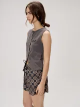 Musculosa MUTMA Trebola de silueta recta confeccionada en tejido de punto color gris con efecto lavado. Posee cierre frontal con botones, detalle de bordado en el pecho y terminación festoneada en el ruedo y las sisas.