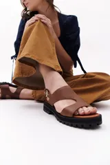 Sandalia de cuero sintético color camel, con plataforma track y hebilla metálica.