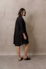 Camisola blanca de silueta amplia y caída liviana, con diseño clásico de cuello camisero, cierre frontal con botones y mangas tres cuartos, decorada con grandes motivos florales bordados.