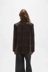 Blazer de corte holgado con diseño a cuadros en tonos marrones y negros. Presenta cuello con solapa, cierre frontal con un botón y bolsillos laterales con solapa.