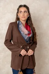 Chaquetón color beige de corte recto y largo, con cierre frontal mediante botones y lazo ajustable en la cintura. Presenta cuello en V, bolsillos laterales con solapa y mangas largas.