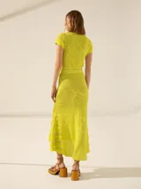 Pollera larga color amarillo, de tejido calado con diseño floral y terminación irregular con flecos.