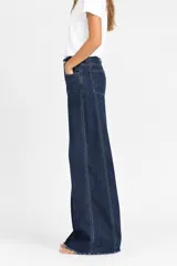Pantalón jean azul de corte ancho tipo wide leg, tiro alto, con costuras pespunteadas visibles a lo largo de las piernas y bolsillos traseros.